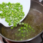 mrożony groszek wrzucany jest do zupy w garnku