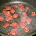 na patelni smażą się plasterki kiełbasy chorizo