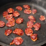 na patelni smażą się plasterki kiełbasy chorizo