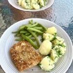 Dorsz w panierce z sezamem smażony podany z gotowanymi ziemniakami i zieloną fasolką szparagową na talerzu