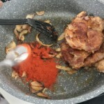 na patelni smażą się dwa kotlety z karczku z cebulą