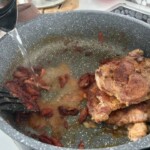 na patelni smażą się dwa kotlety z karczku z cebulą