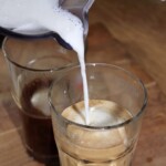 wlewanie spienionego mleka do szklanki z zimną kawą