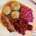 szare kluski śląskie na talerzu z roladą śląską i modrą kapustą