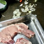 dwa kotlety schabowe surowe w naczyniu metalowym