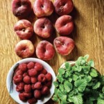 świeże brzoskwinie, maliny i pęczek świeżej mięty na stole