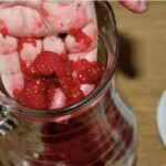 na dłoni znajdują się zmiażdżone maliny