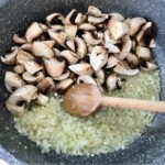 na patelni smażą się pokrojone pieczarki razem z cebulą