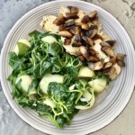 Pierś kurczaka z pieczarkami na talerzu podana z ziemniakami i szpinakiem