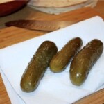 trzy ogórki kiszone leżą na ręczniku papierowym