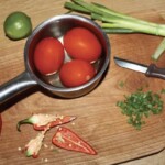 trzy duże pomidory parzą się w gorącej wodzie w garnku