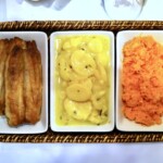 Śledzie smażone podane ze startą marchewką oraz ziemniakami na kwaśno