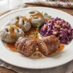 szare kluski śląskie na talerzu podane z roladą śląską i modrą kapustą