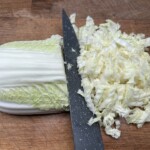 kapusta pekińska siekana jest dużym nożem na desce kuchennej