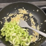 na patelni smażą się kawałki selera naciowego razem z ziemniakami krojonymi w kostkę oraz drobno siekaną cebulą