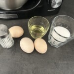 trzy jajka, szklanka cukru i szklanka oleju na blacie kuchennym