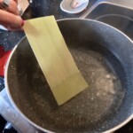 do dużego garnka z gotującą się wodą wkładane są płaty makaronu lasagne